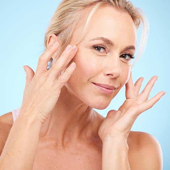 Woman, portrait and facial beauty to touch skincare, mockup and blue background for wellness cosmetics. Studio model, face and healthy aesthetic of laser dermatology, natural shine and salon results